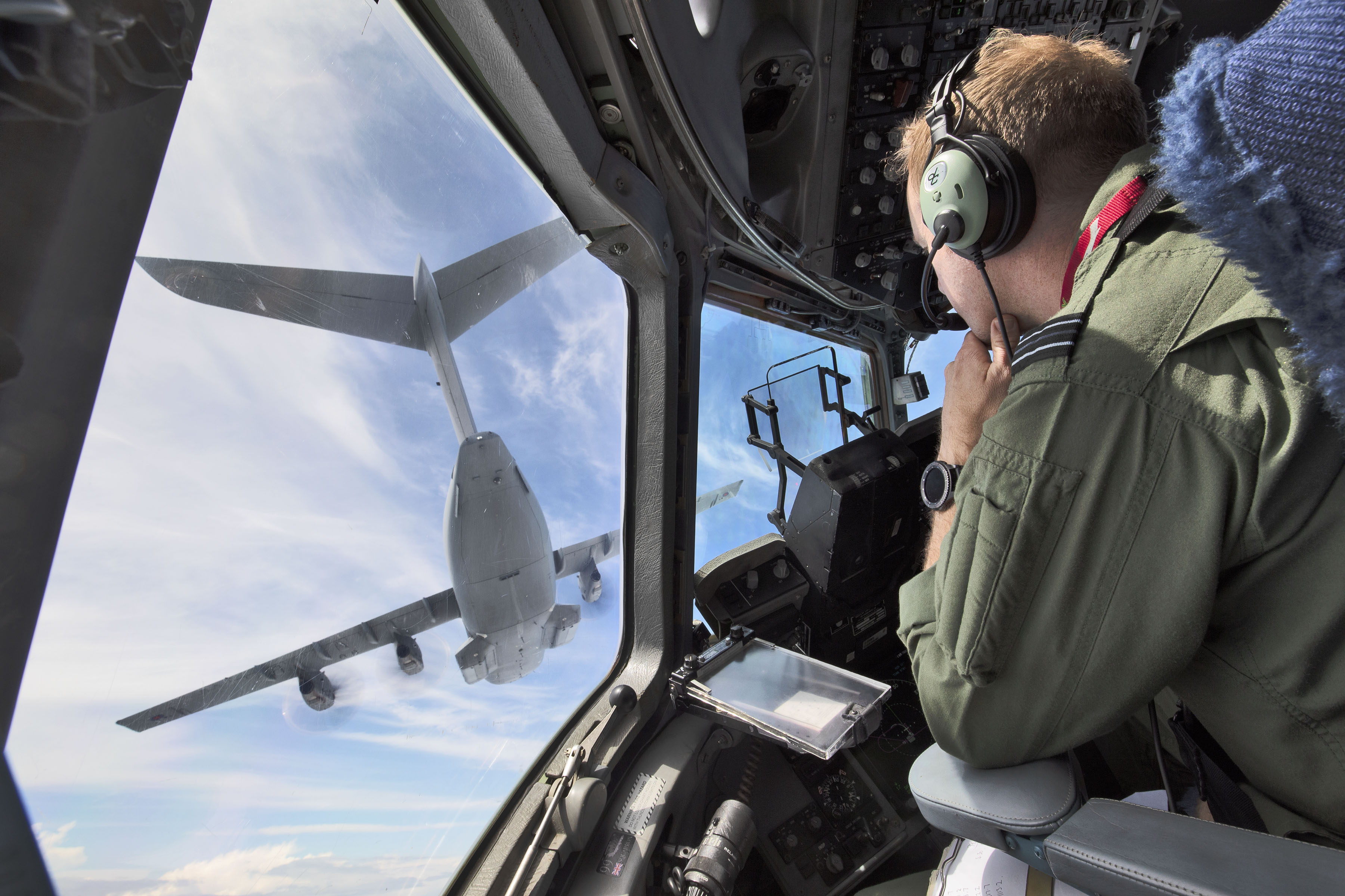 Pilots in the cockpit look out to another aircraft in flight.